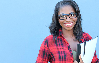 Young woman holding a stack of papers, wearing glasses and smiling