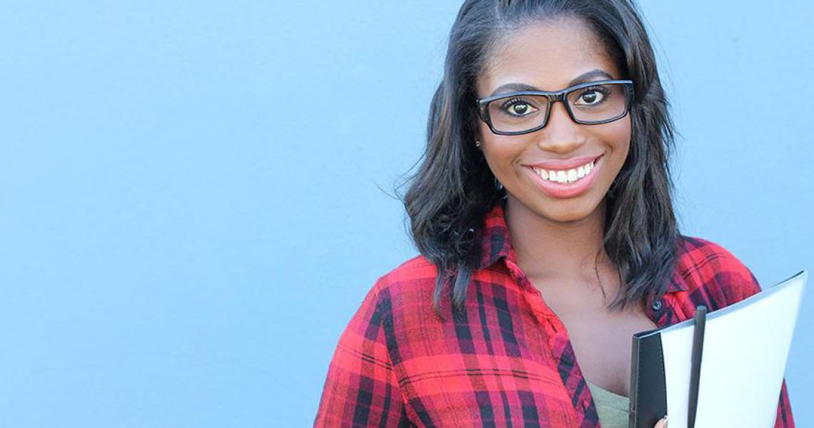 Young woman holding a stack of papers, wearing glasses and smiling